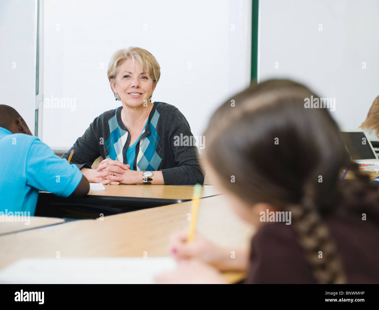 Teacher watching over students in elementary classroom Stock Photo