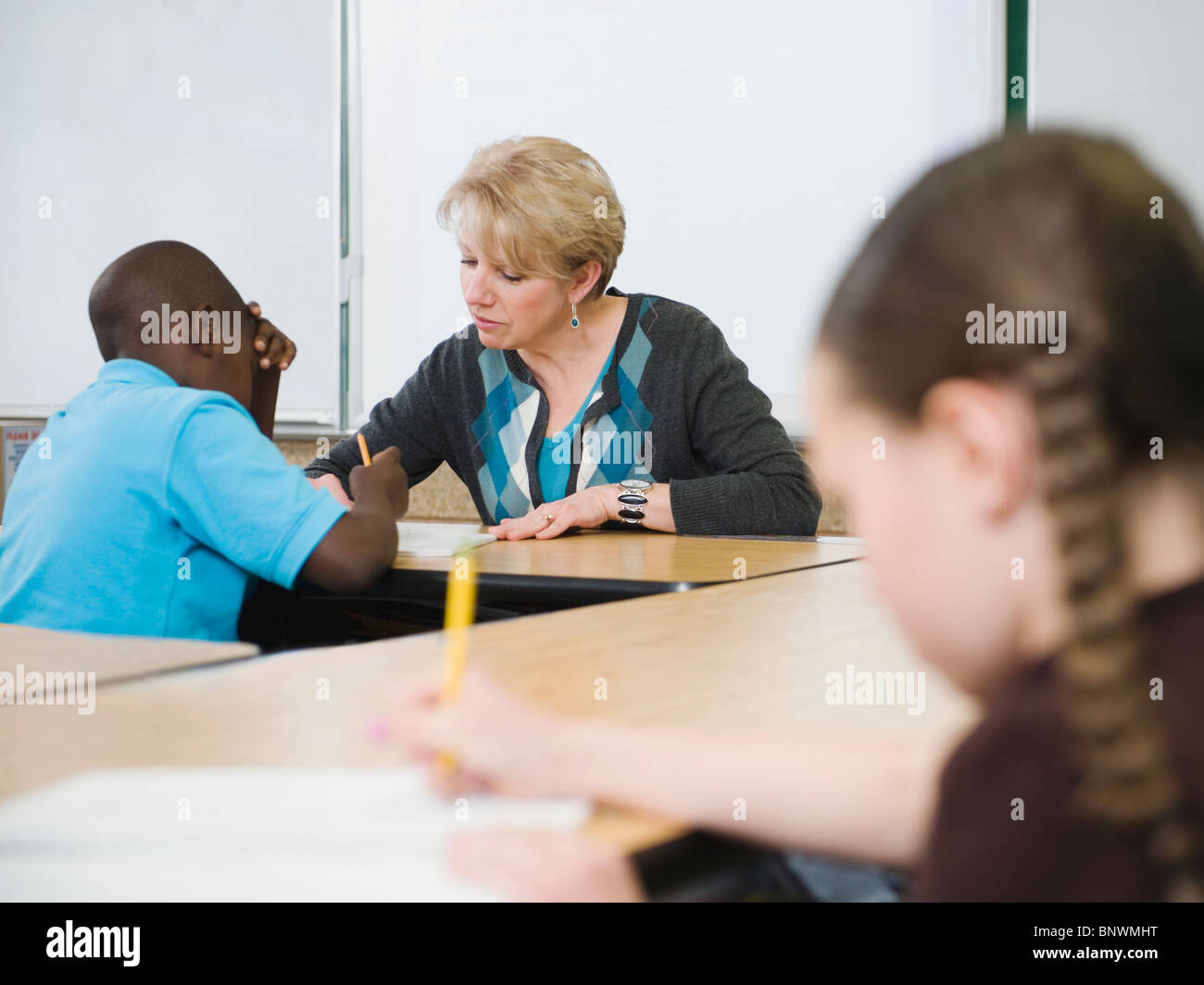 Teacher helping student in elementary school classroom Stock Photo
