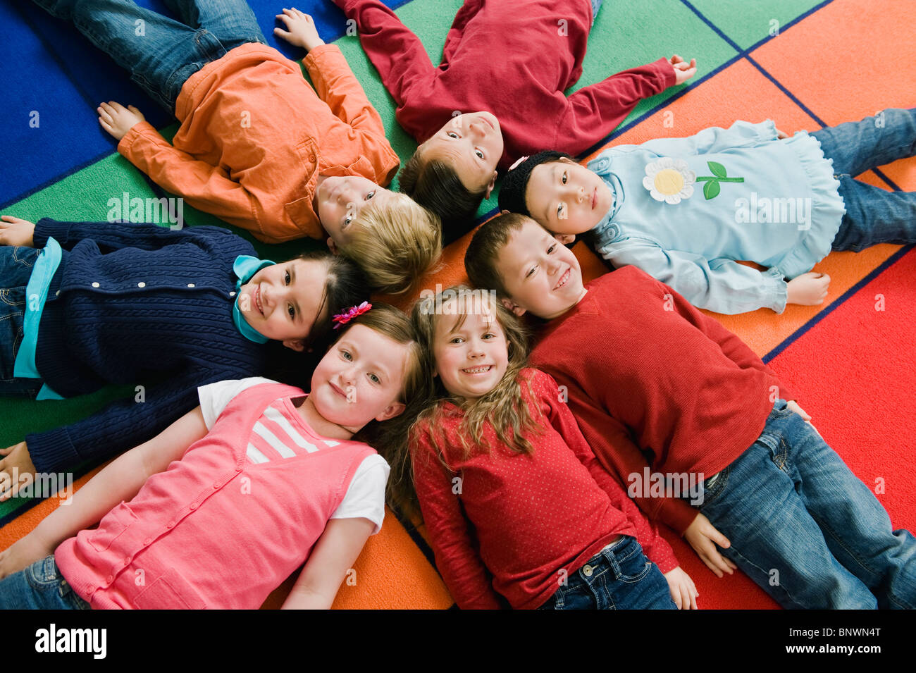 Kindergarten students lying in a circle on floor mats Stock Photo