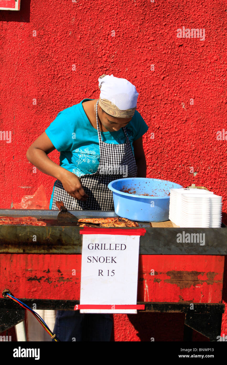 Local woman grilling freshly caught snoek at Hout Bay harbour near Cape Town, South Africa. Stock Photo