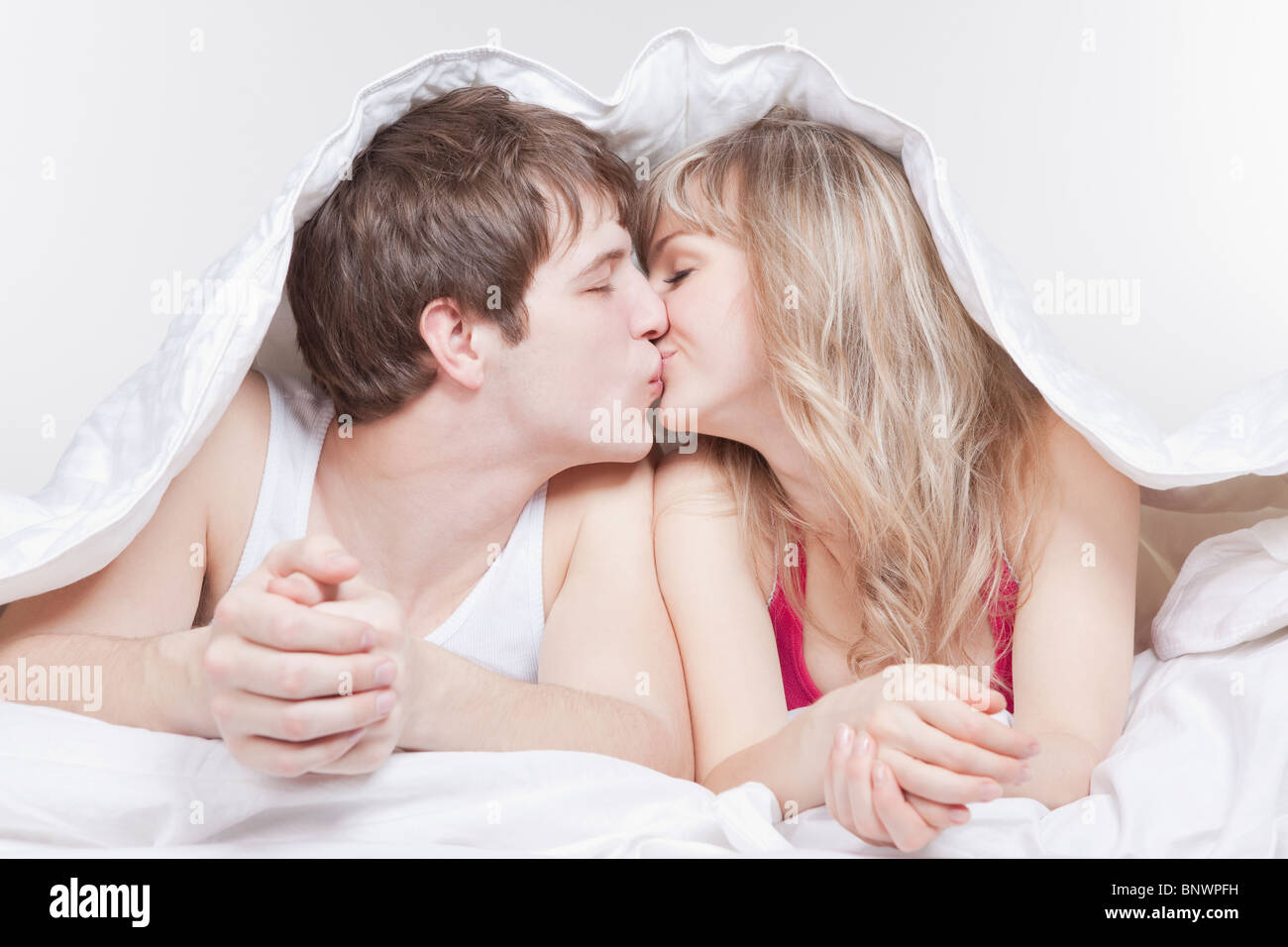 Couple kissing under the covers Stock Photo