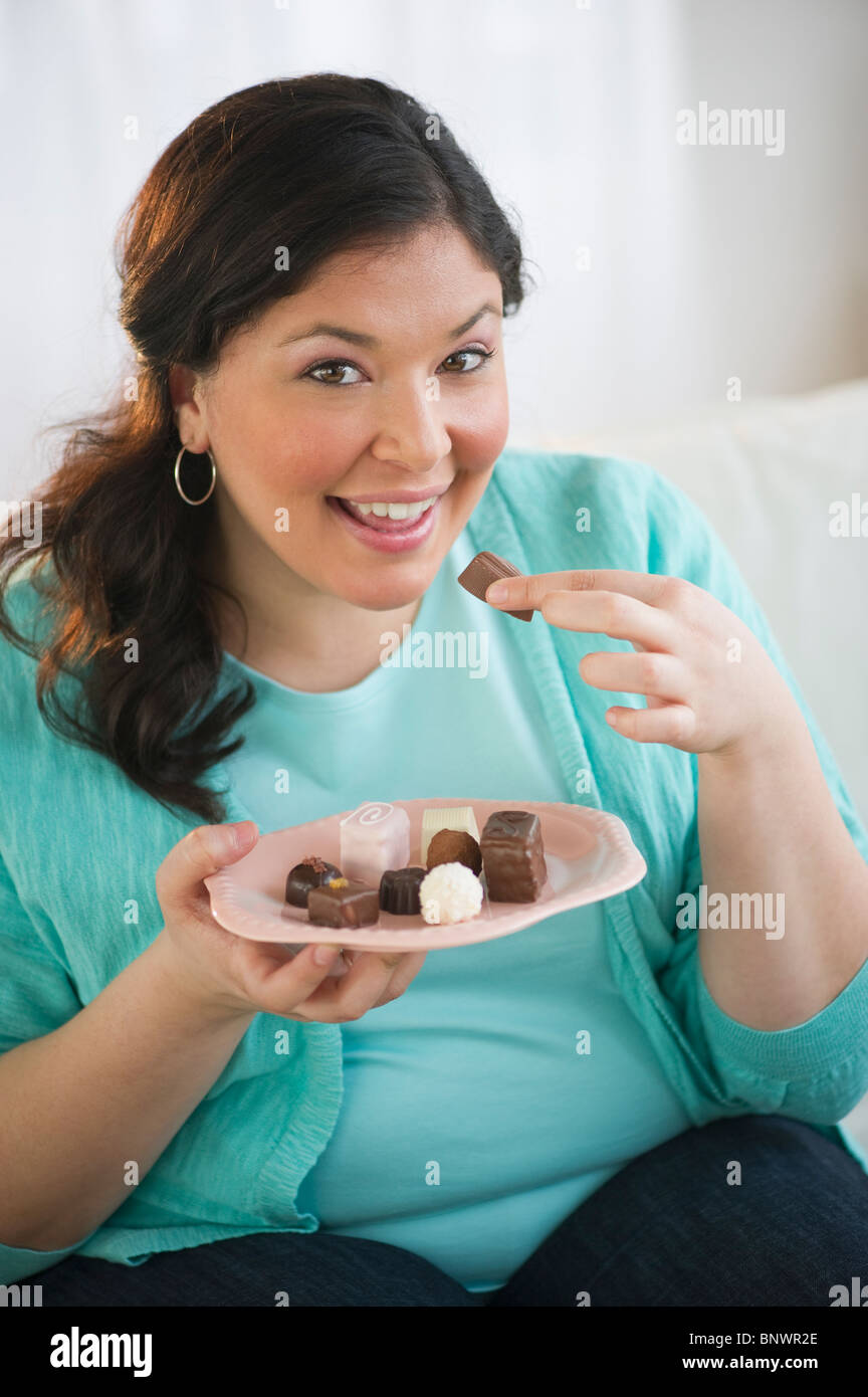 Overweight woman eating chocolates Stock Photo