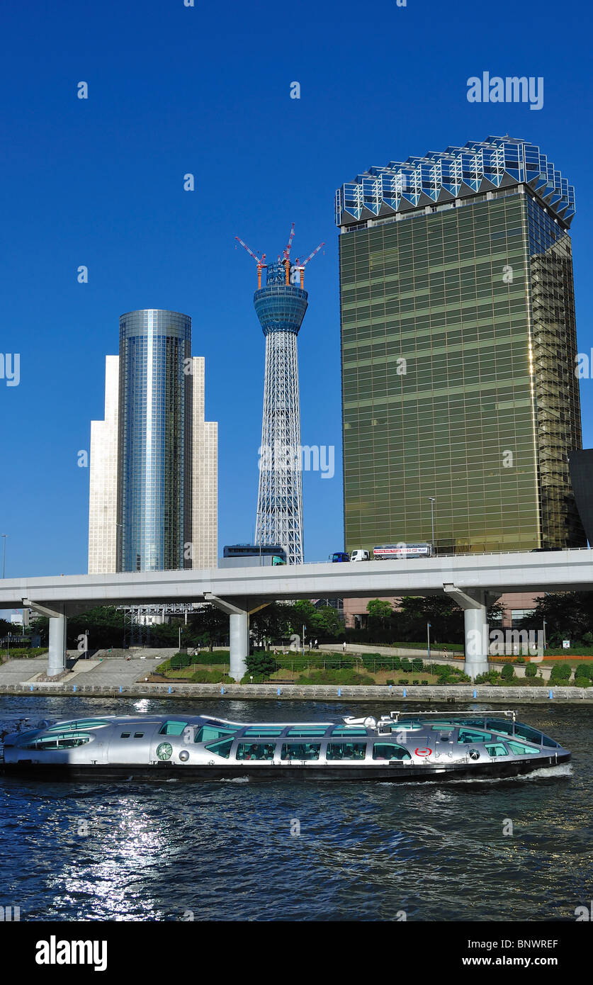 Sightseeing boat with Asahi brewery next to the new 'Tokyo Sky Tree' TV tower under construction in Tokyo`s Asakusa area (Japan) Stock Photo
