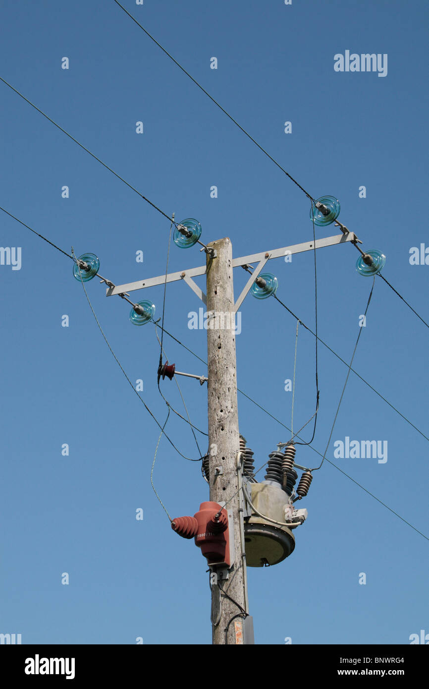 A power line (wires/cables) and transformer on a wooden telegraph pole on the edge of a field near Bridport, Dorset, UK. Stock Photo