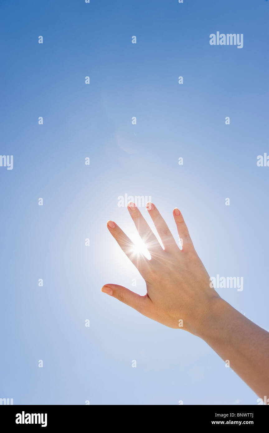 Hand held up in front of sunshine Stock Photo
