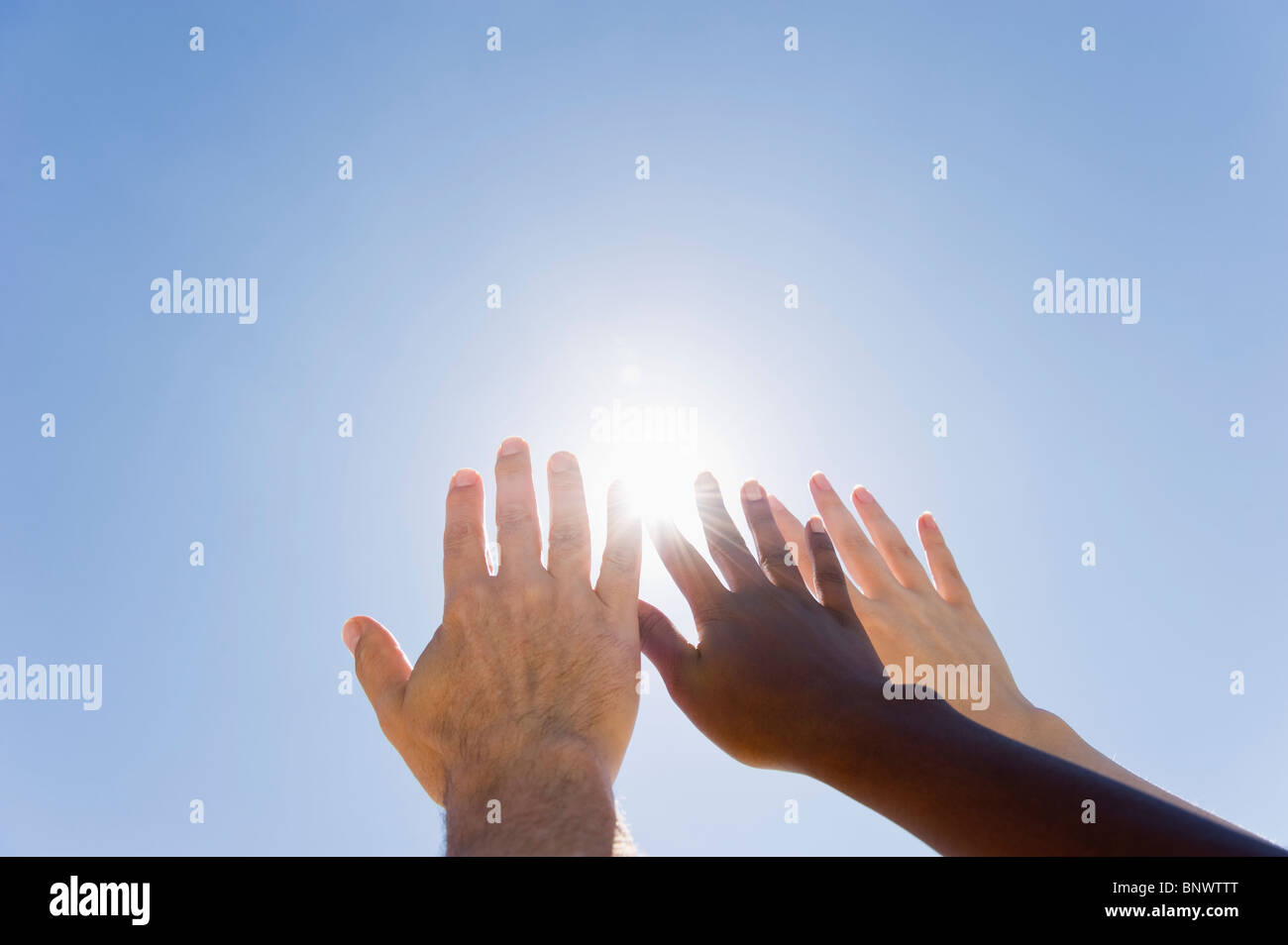 Hands held up in front of sunshine Stock Photo