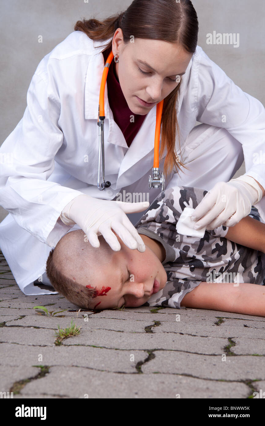 Female doctor looking at young boy with bleeding head Stock Photo