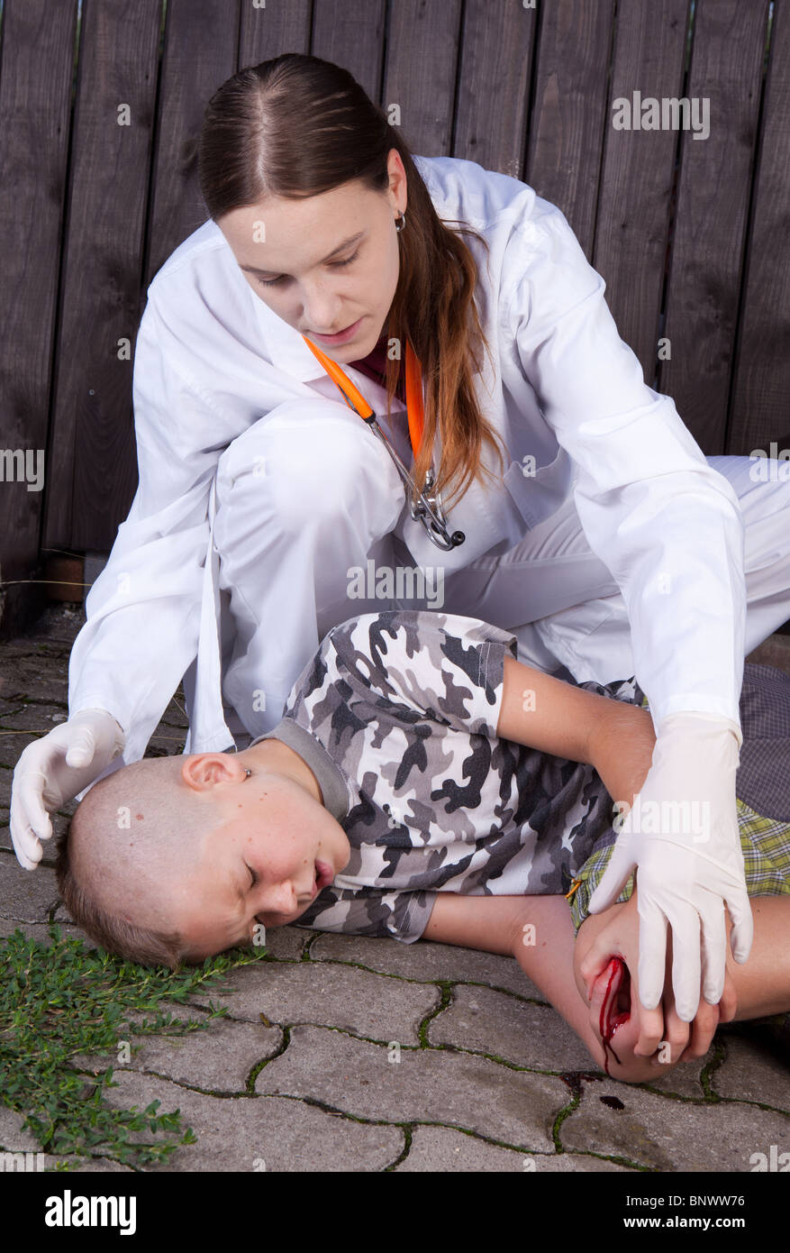 Female doctor looking at young boy with bleeding knee Stock Photo