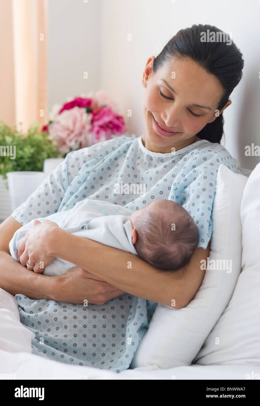 Mother holding newborn baby in hospital bed Stock Photo