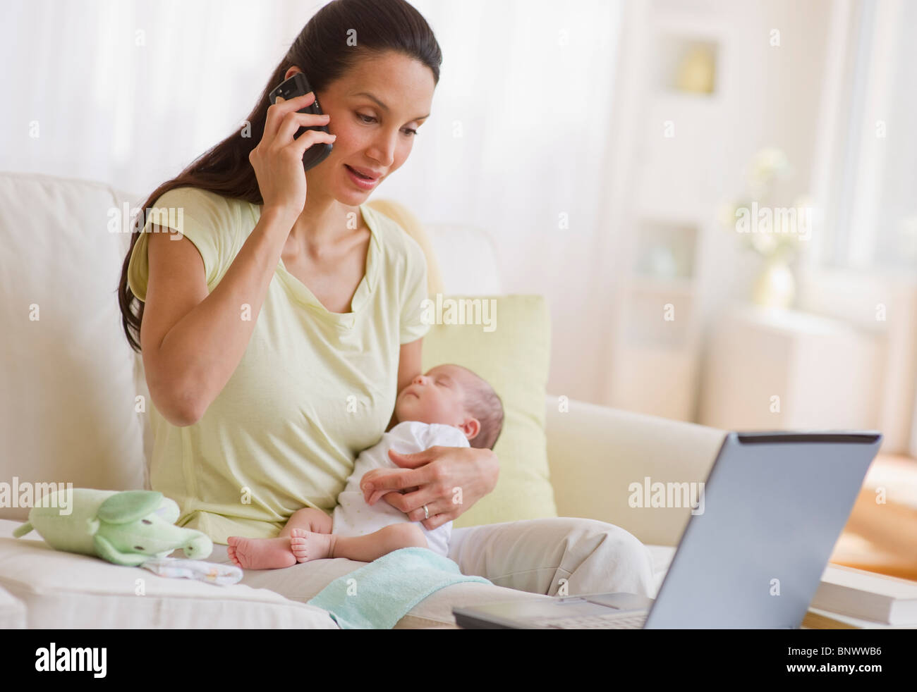 Mother talking on phone while holding her baby Stock Photo