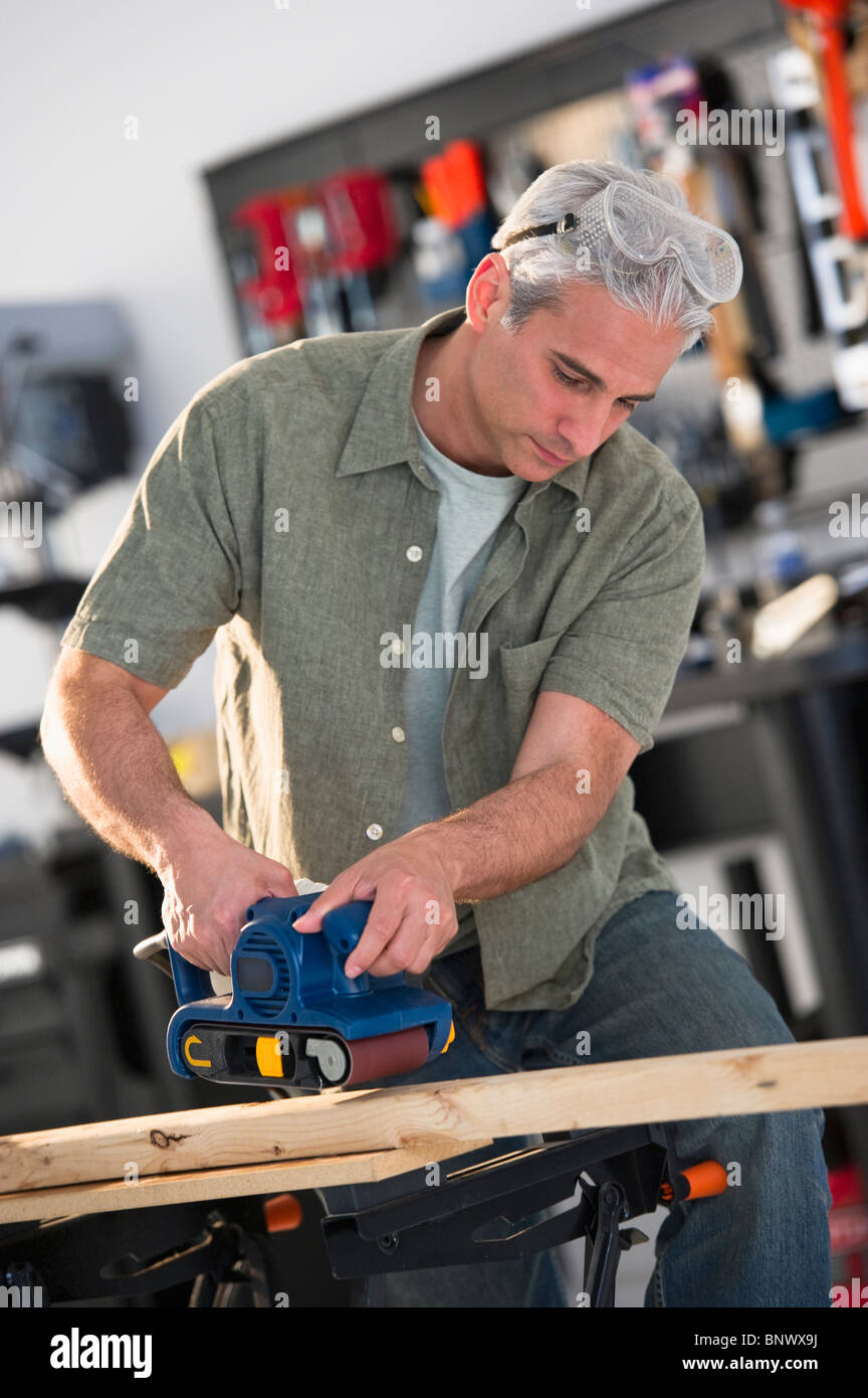 Handyman sanding a piece of wood in workshop Stock Photo