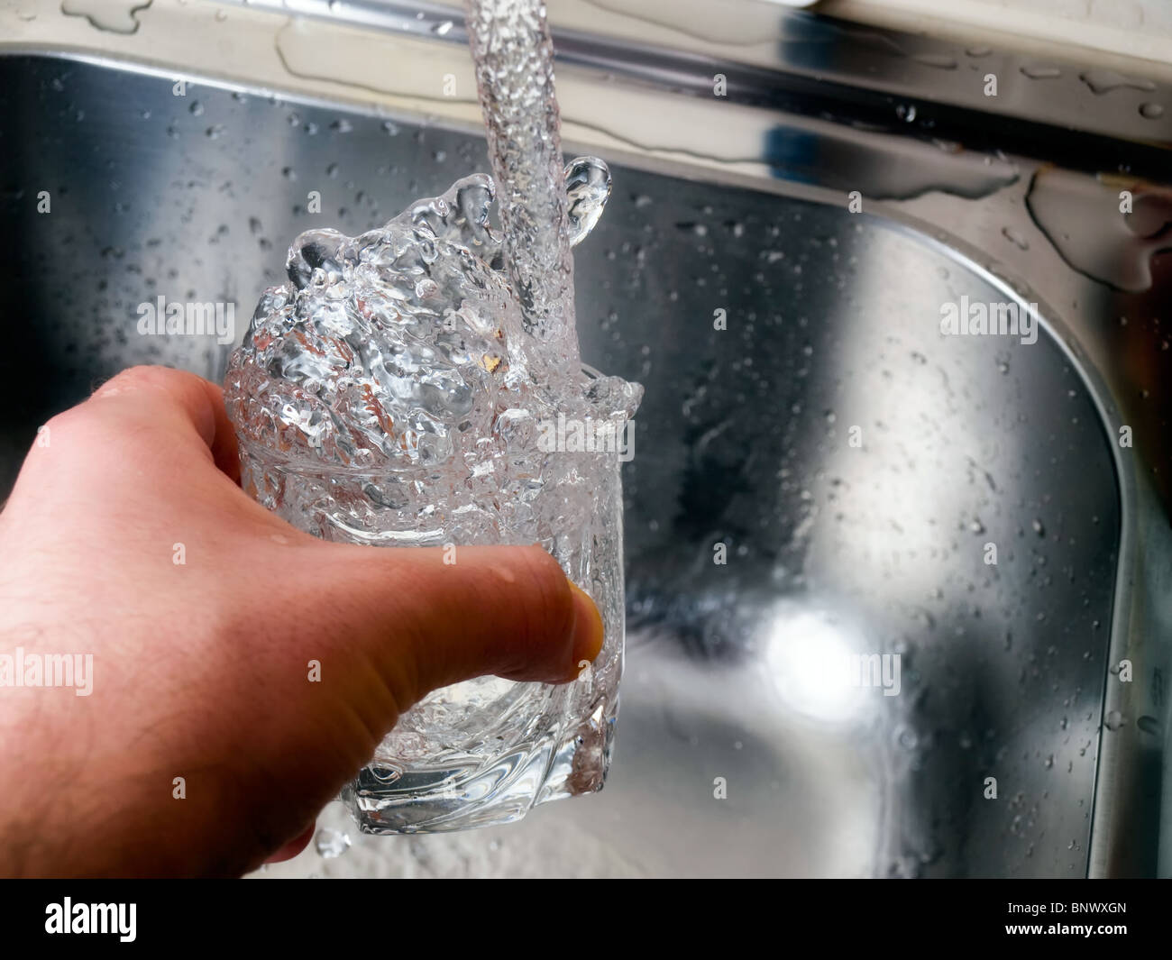 Moment during the filling of water in a glass... Stock Photo