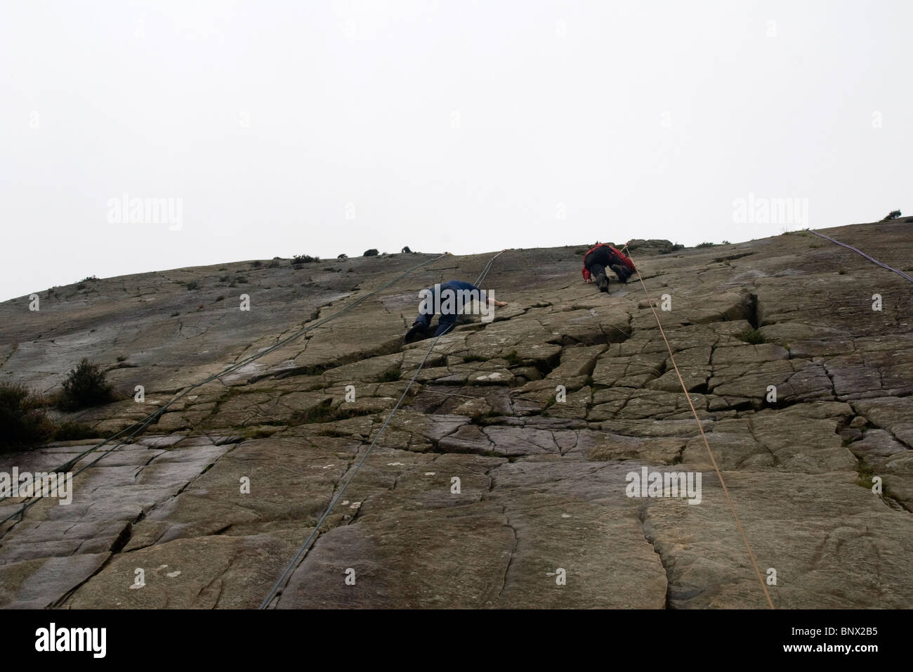 Two Men rock climbing at Barmouth Slabs nr Barmouth Gwynedd Mid Wales