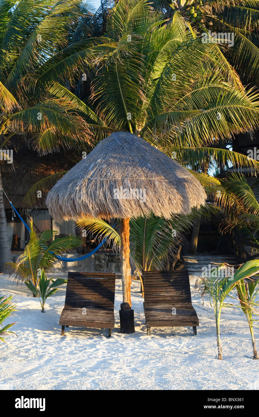 Palapa flanked by 2 wooden lounge chairs on the beach of Isla Holbox, state of Quintana Roo, Mexico. Stock Photo