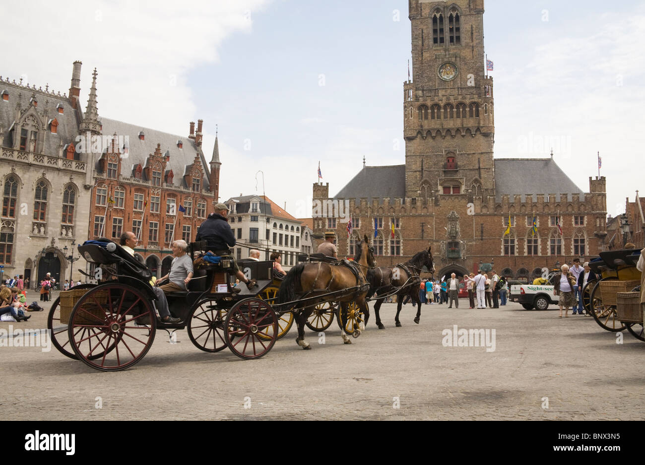 Bruges Belgium Europe EU Horse drawn carriages crossing Markt square taking tourists on a city tour Stock Photo