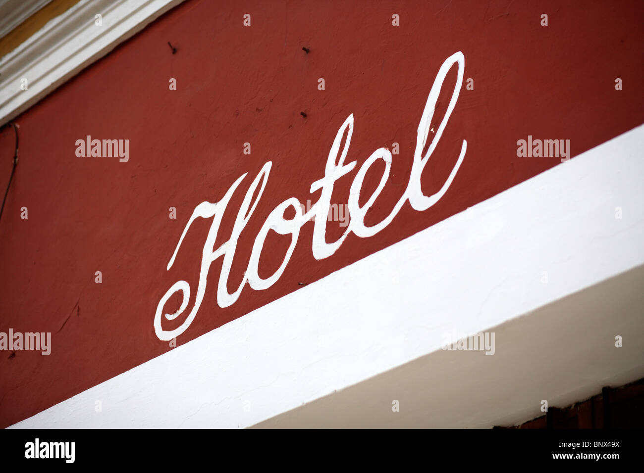 A sign for a hotel painted onto a colourful red wall in Antigua near Guatemala City Stock Photo