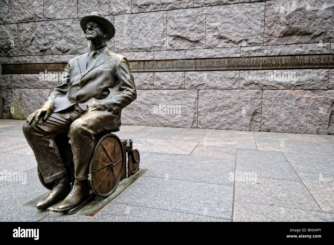 Franklin D Roosevelt Memorial FDR Wheelchair Statue Washington DC // WASHINGTON DC — A sculpture depicts President Franklin D. Roosevelt in a wheelchair at the Franklin D. Roosevelt Memorial. The bronze sculpture shows Roosevelt as a younger man, representing his leadership during the Great Depression and World War II while acknowledging his disability. The memorial, dedicated in 1997, spans 7.5 acres (3 hectares) along the Tidal Basin and chronicles Roosevelt's four terms in office from 1933 to 1945. This particular sculpture was added following advocacy from disability rights groups who felt Stock Photo