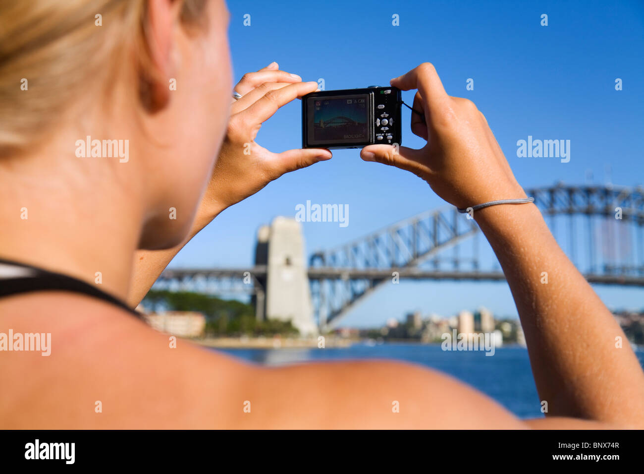 A woman photographs the Harbour Bridge in Sydney, New South Wales