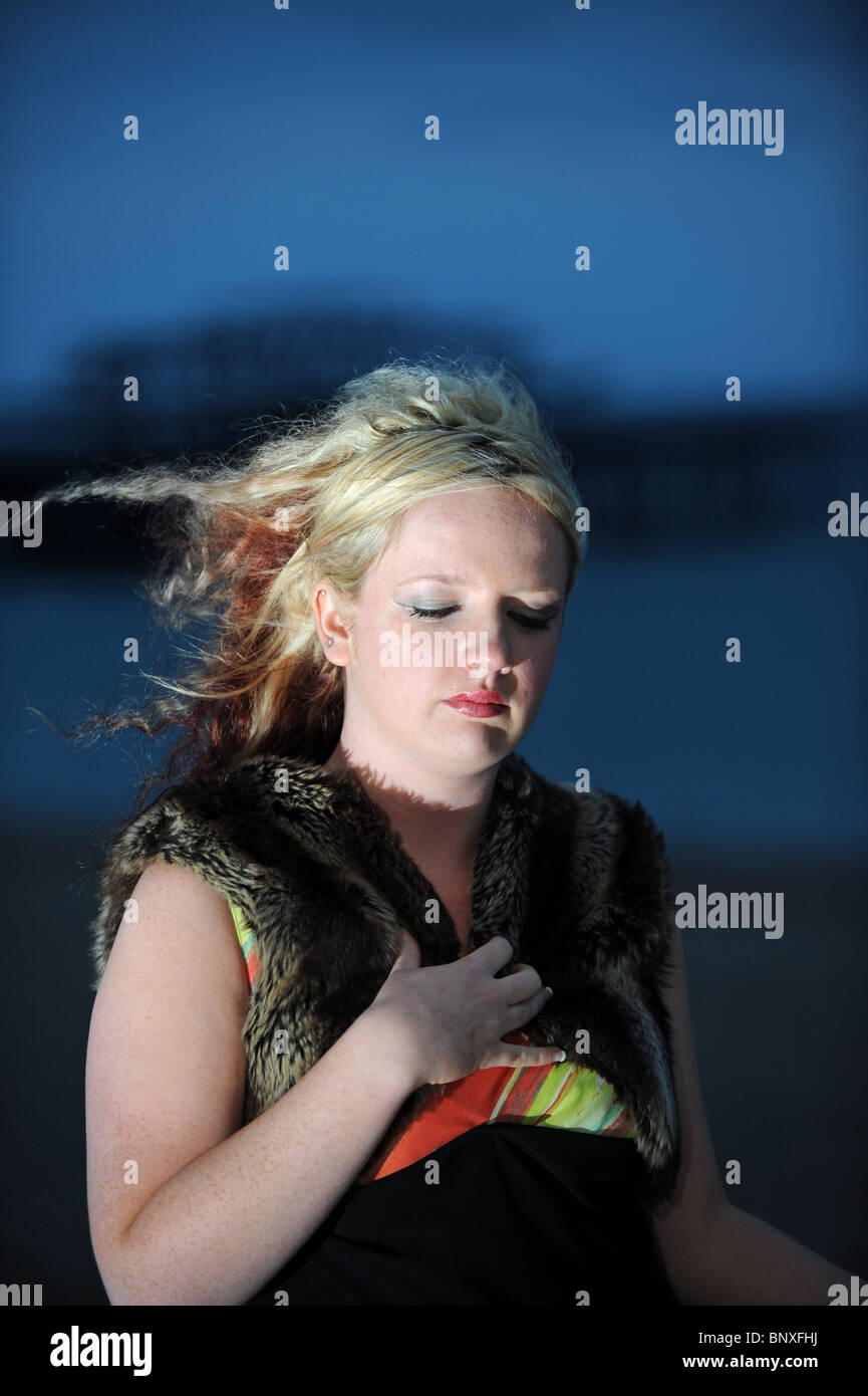 Blonde hair model with avant garde style fashion black dress on Brighton seafront near the West Pier UK Stock Photo