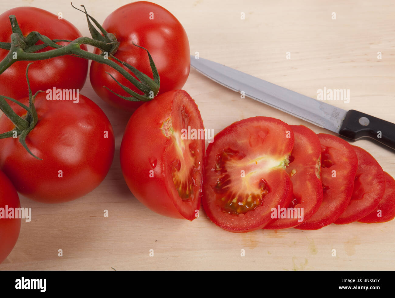 Sliced Tomatoes on Wooden Chopping Board with a Knife Stock Photo - Alamy