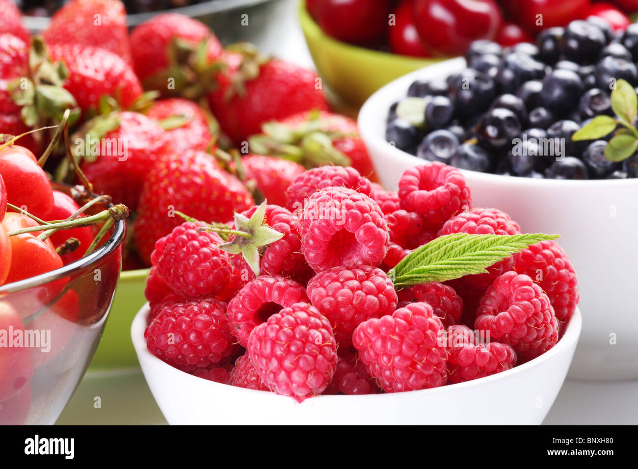 Different berries in bowls. Bowl with tempting raspberries in a front. Stock Photo