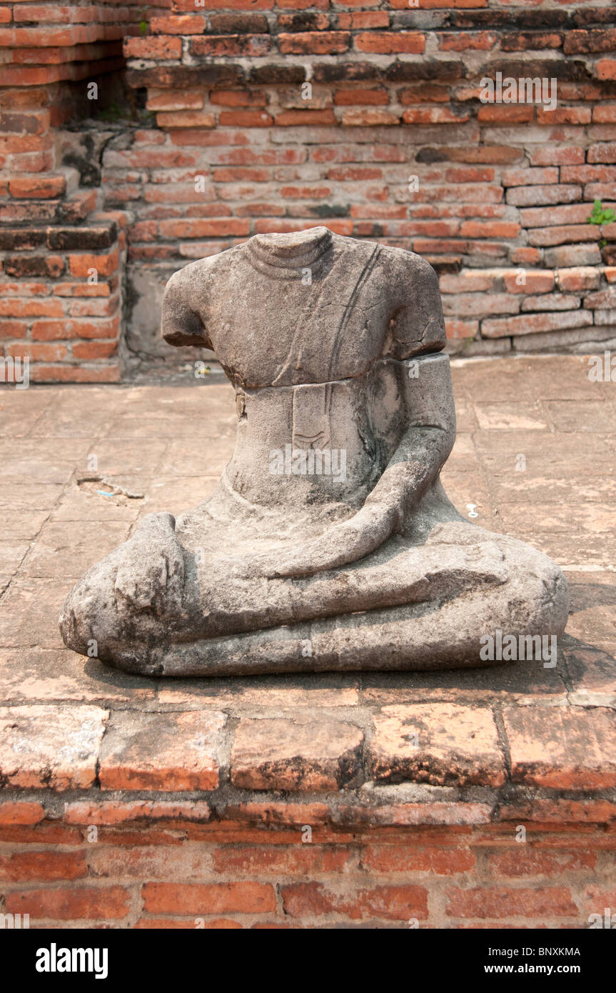 Headless Buddha stone statue sitting against brick wall in Thailand Stock Photo