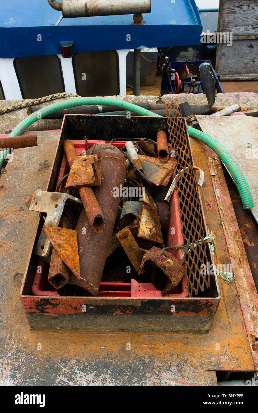A box of rusting bits and pieces of iron on the quay Stock Photo