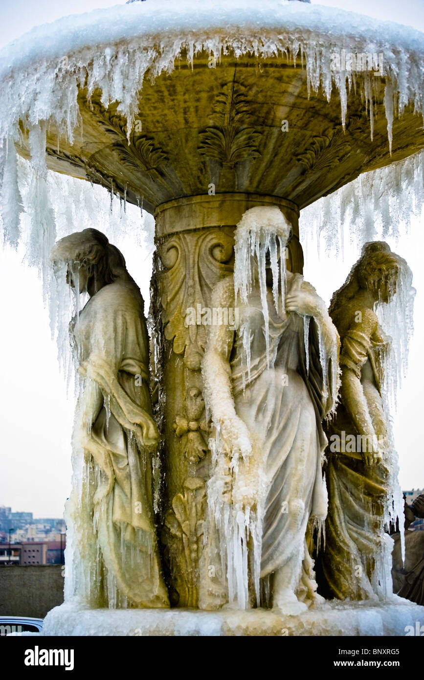 Frozen fountain, icicles obscuring faces of statues Stock Photo