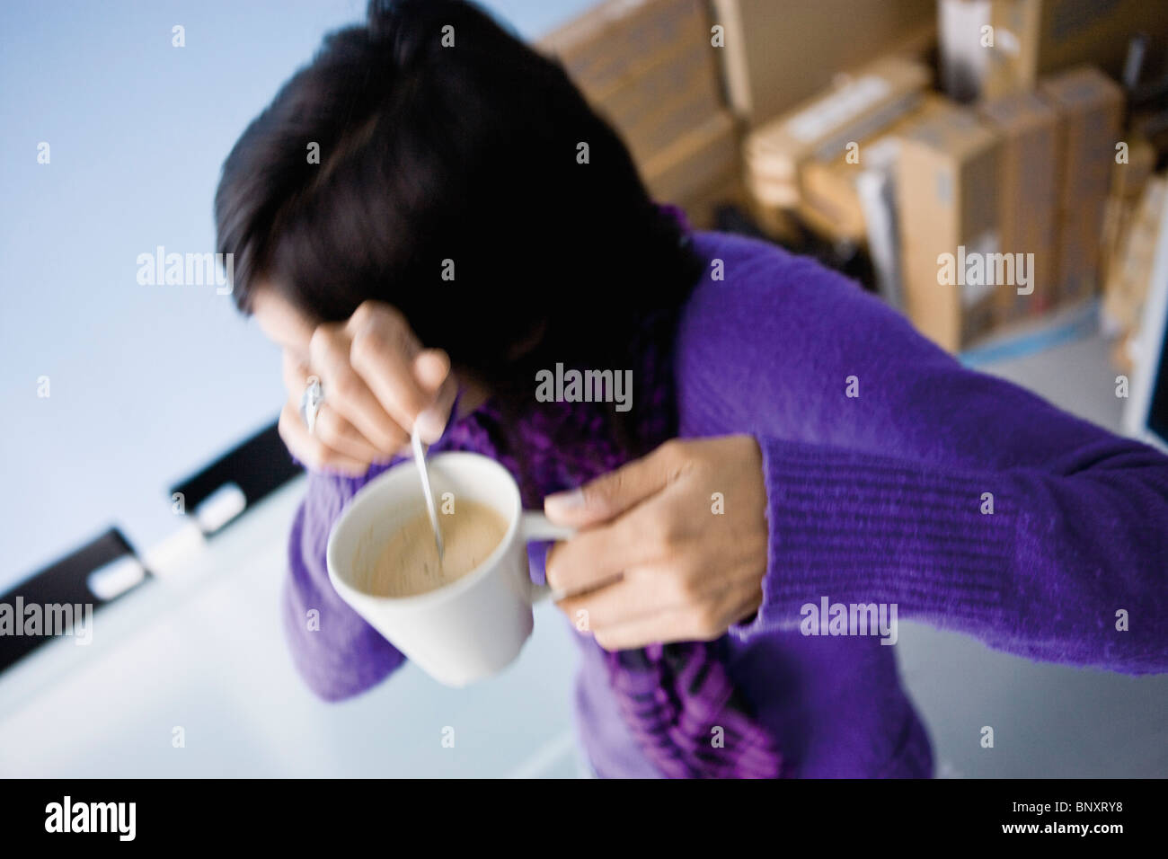 Woman turning away from camera, shyly covering face, coffee cup in hands Stock Photo