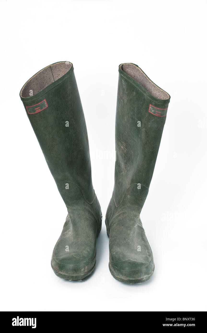 A pair of old used worn green wellington boots against a white ...