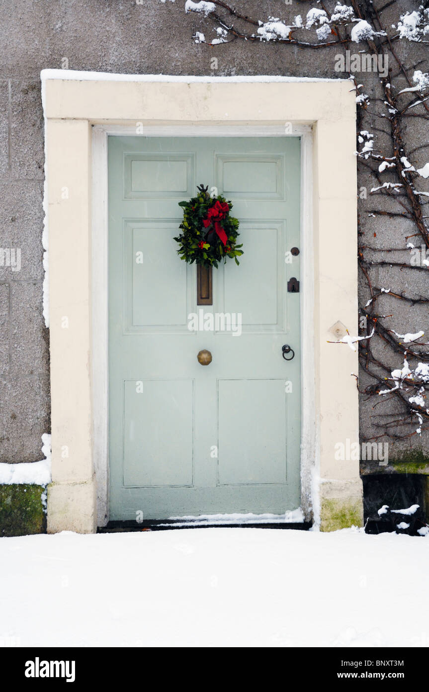 A front door and Christmas decoration surrounded by fresh snowfall. Stock Photo
