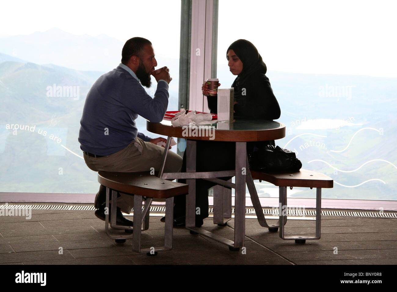 Couple drinking at Mount Snowdon summit cafe, Snowdonia National Park, North Wales, UK Stock Photo