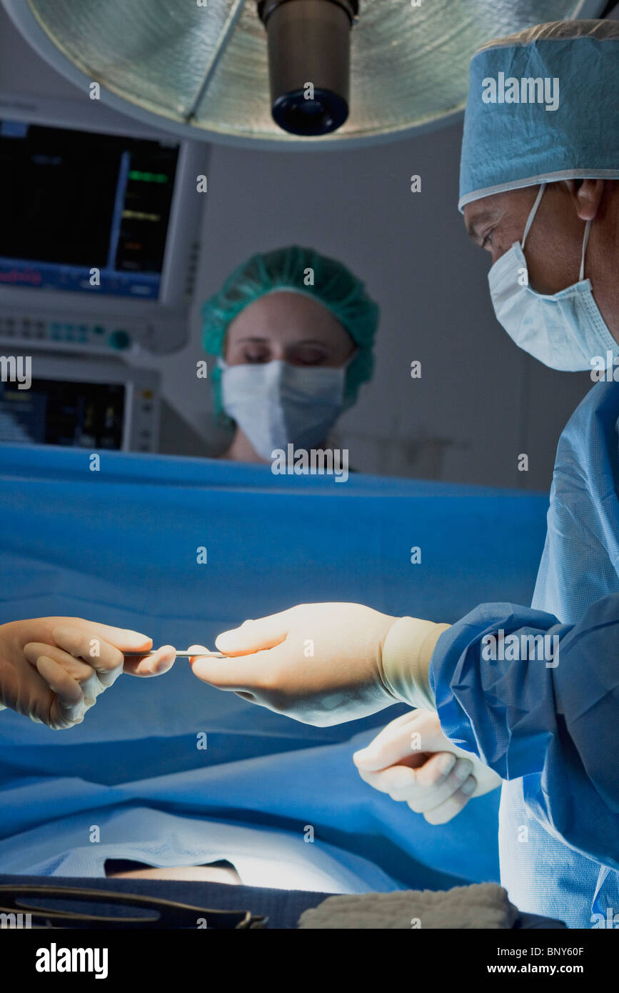 Handing surgical instrument to surgeon during operation Stock Photo Alamy