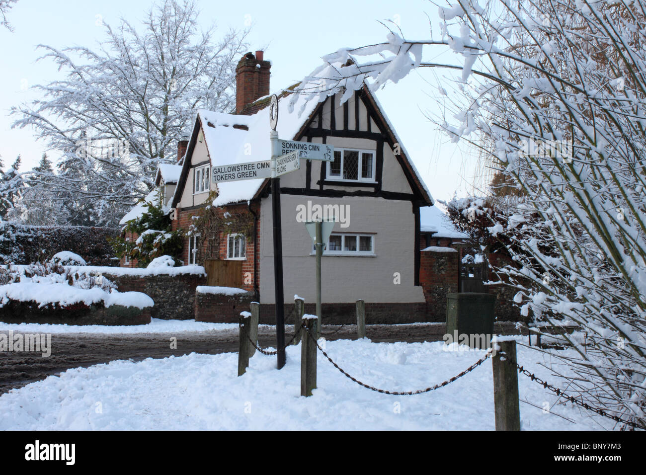 Half timbered House and signpost at Kidmore End in deep snow, Reading, Oxfordshire, England, UK Stock Photo
