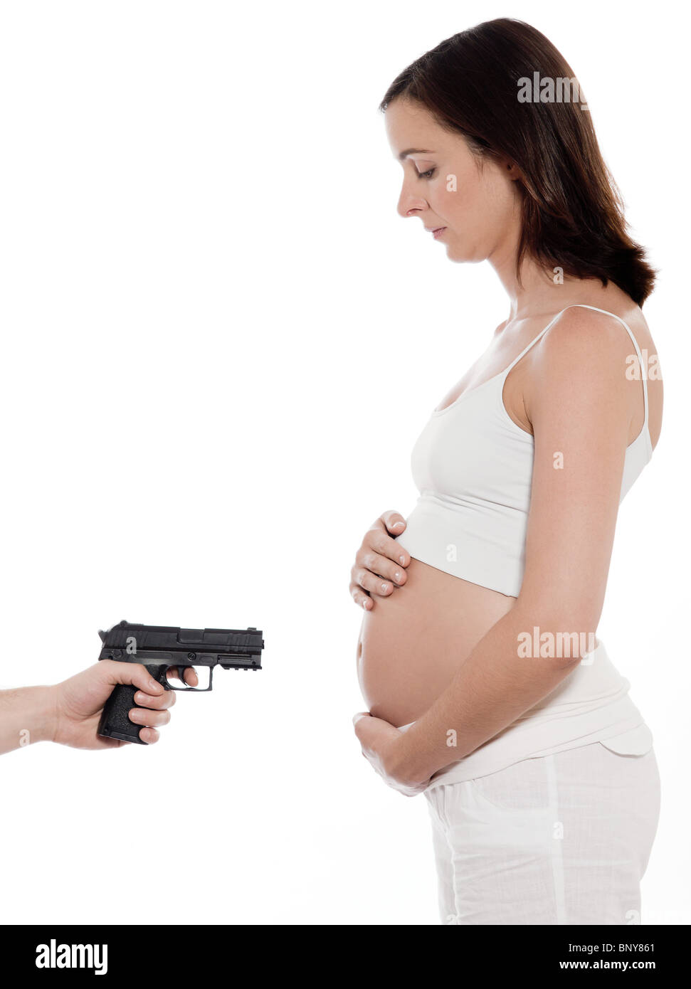 pregnant caucasian woman portrait gun point on belly isolated studio on white background Stock Photo