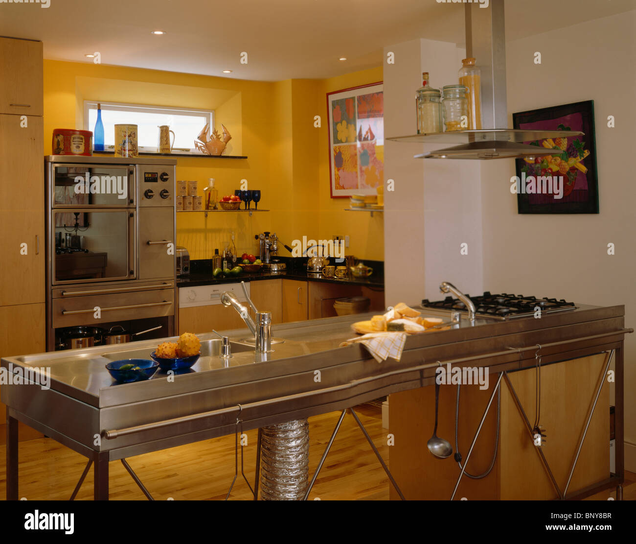 Stainless steel freestanding double sink and hob unit in modern yellow kitchen Stock Photo