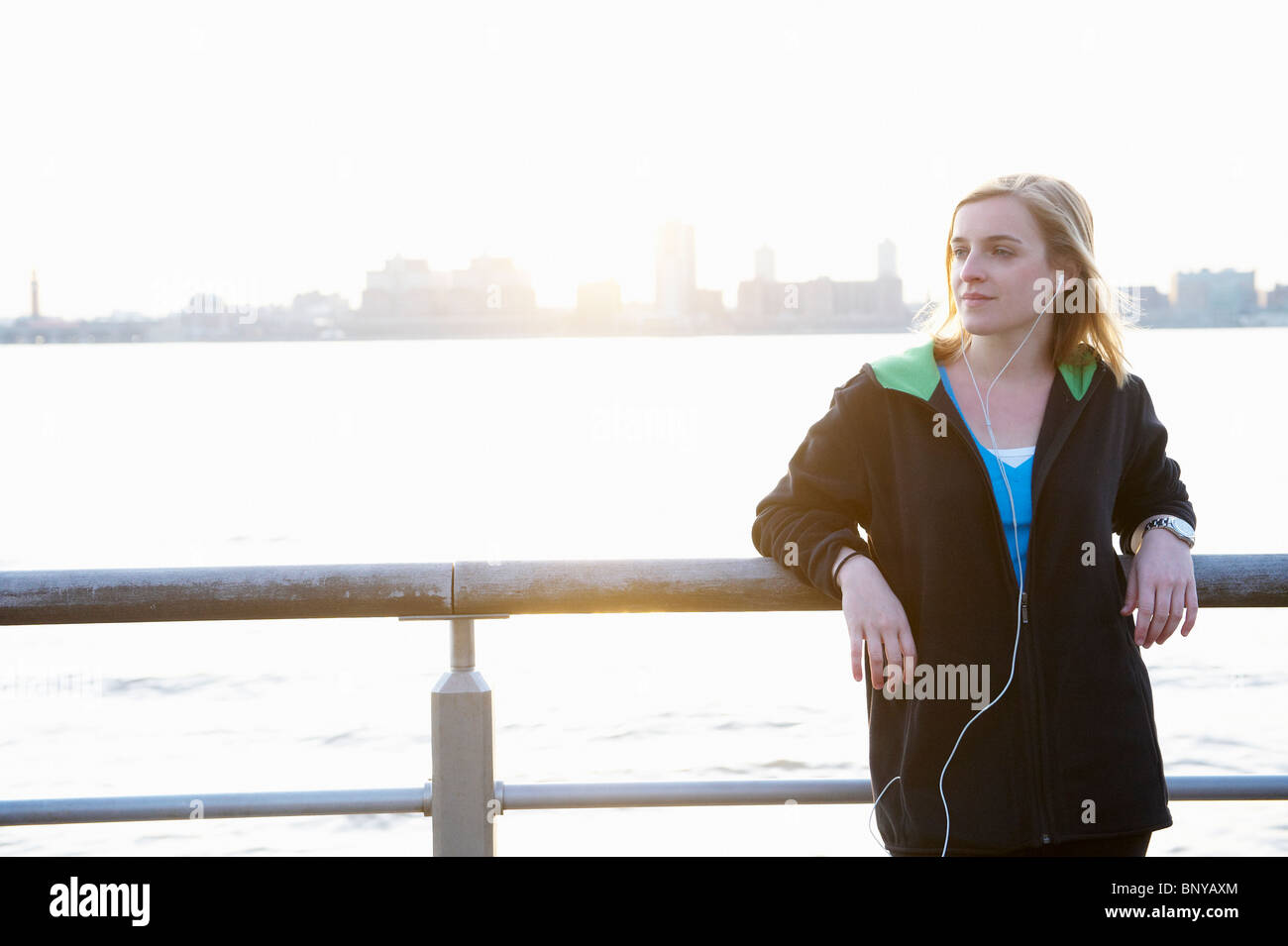 Woman leaning against a fence, with ipod Stock Photo