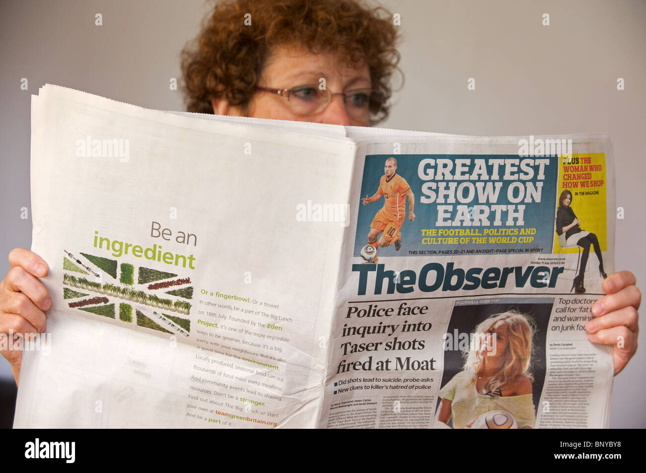 Woman reading a copy of The Observer newspaper Stock Photo