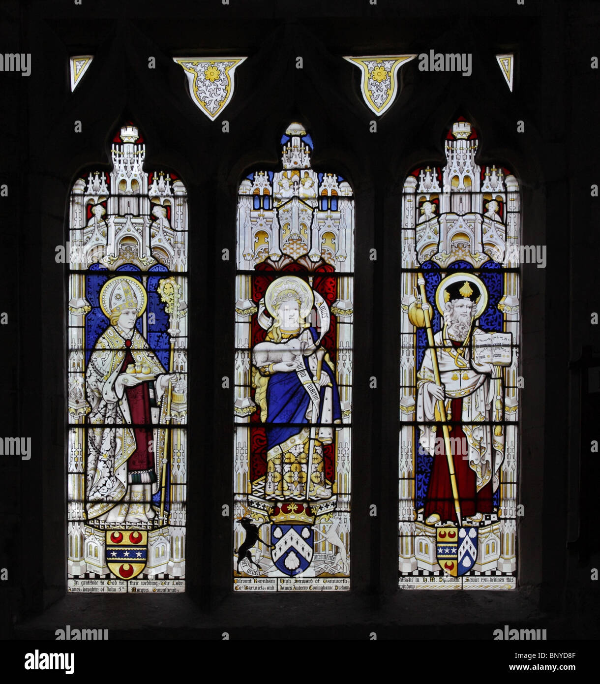 A stained glass window by Geoffrey Webb of 1911 depicting Saints Nicholas, Agnes with lamb and James the Greater, Apostle Stock Photo
