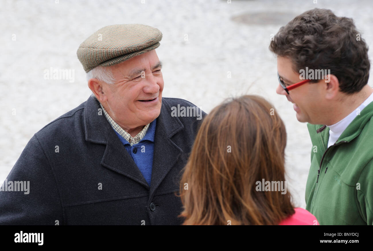 A senior male talking in the street to a couple in their 30´s Village life Aracena Andalucia Spain Stock Photo