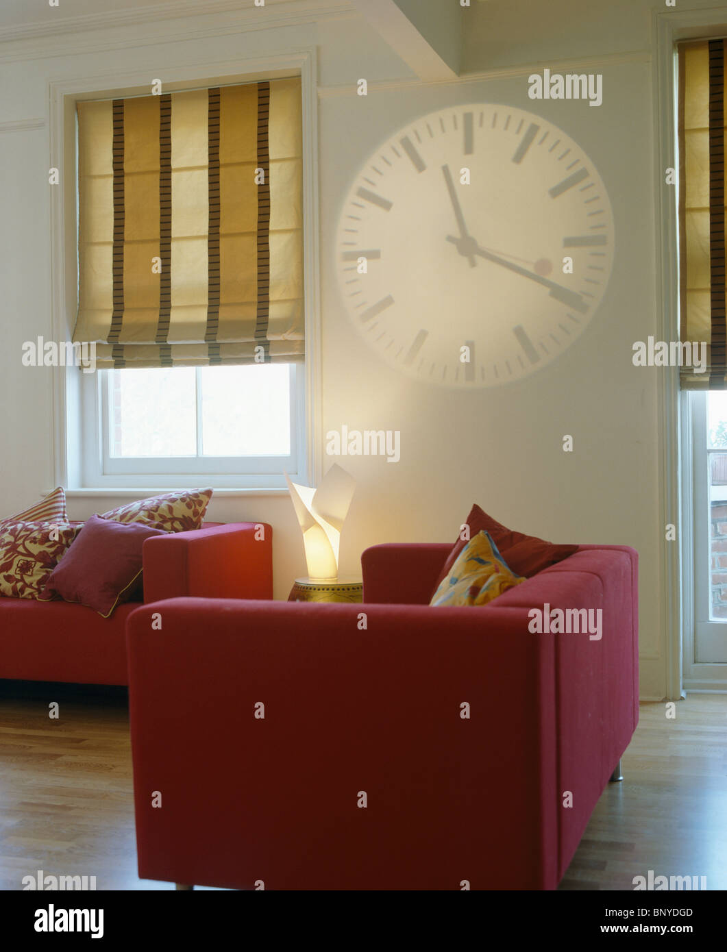 Hologram clock on wall beside window with wide-striped beige blinds inn ...