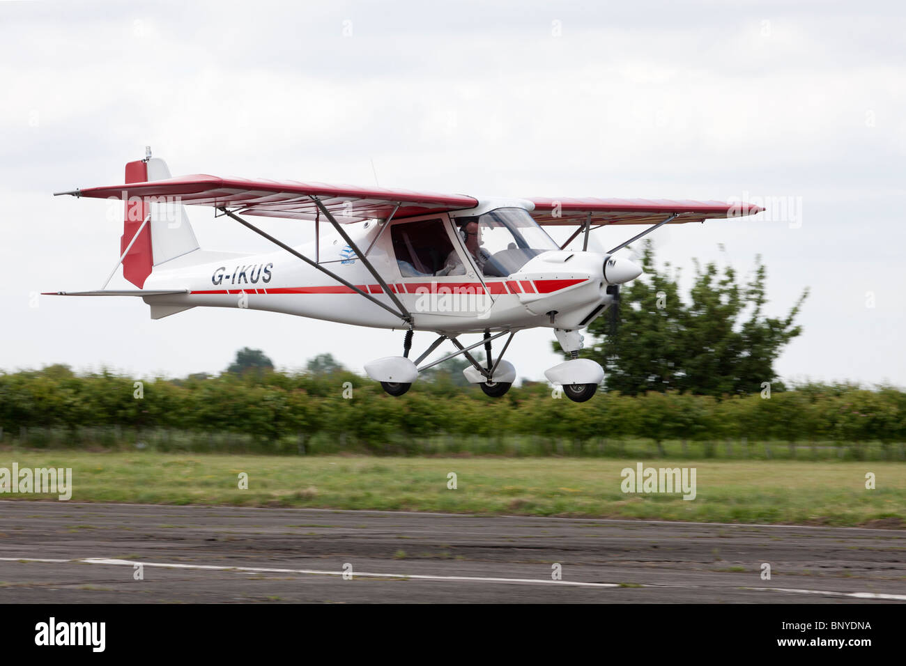 Ikarus C42 FB UK G-IKUS in flight on final approach to land at Wickenby Airfield Stock Photo