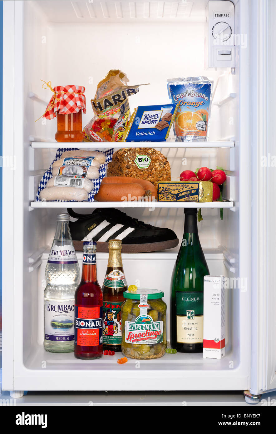 Various food products and a sports shoe in a fridge, Berlin, Germany Stock Photo