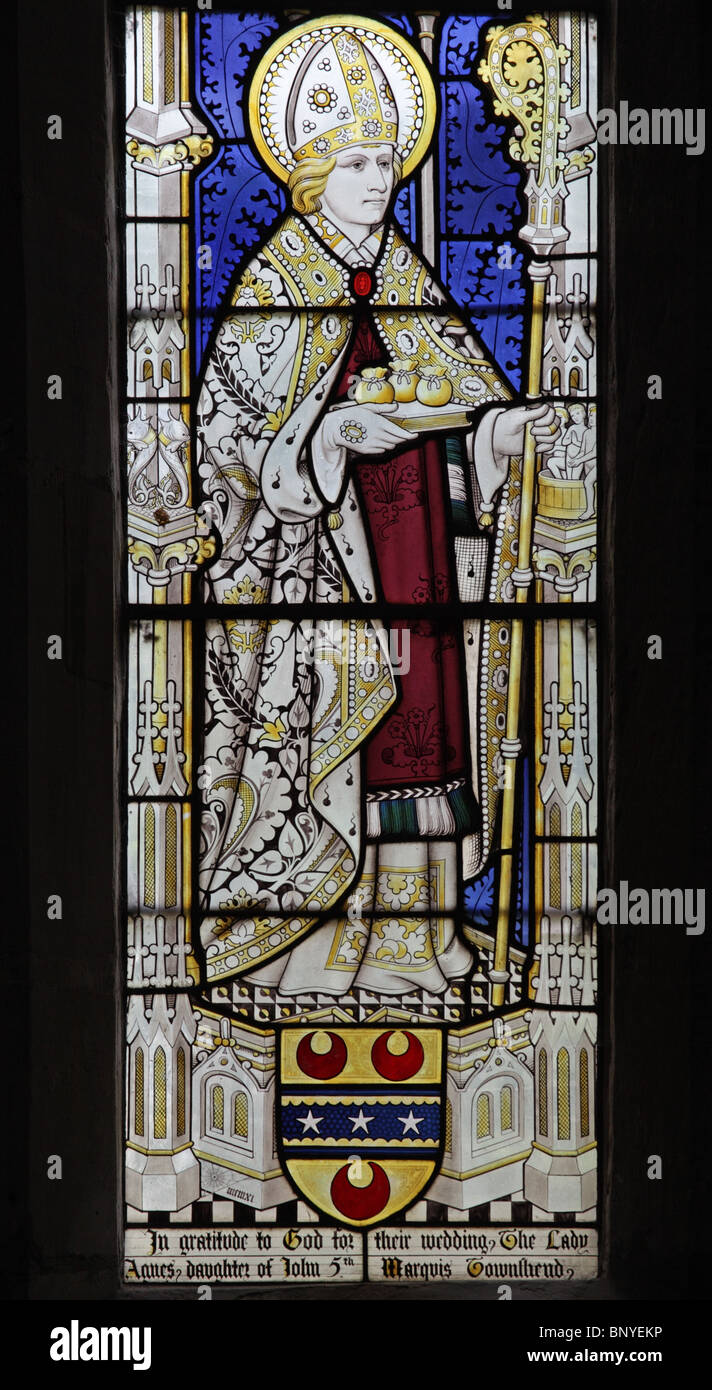 A stained glass window by Geoffrey Webb depicting Saint Nicholas of Myra holding three bags of gold and dressed as Bishop of Myra Stock Photo