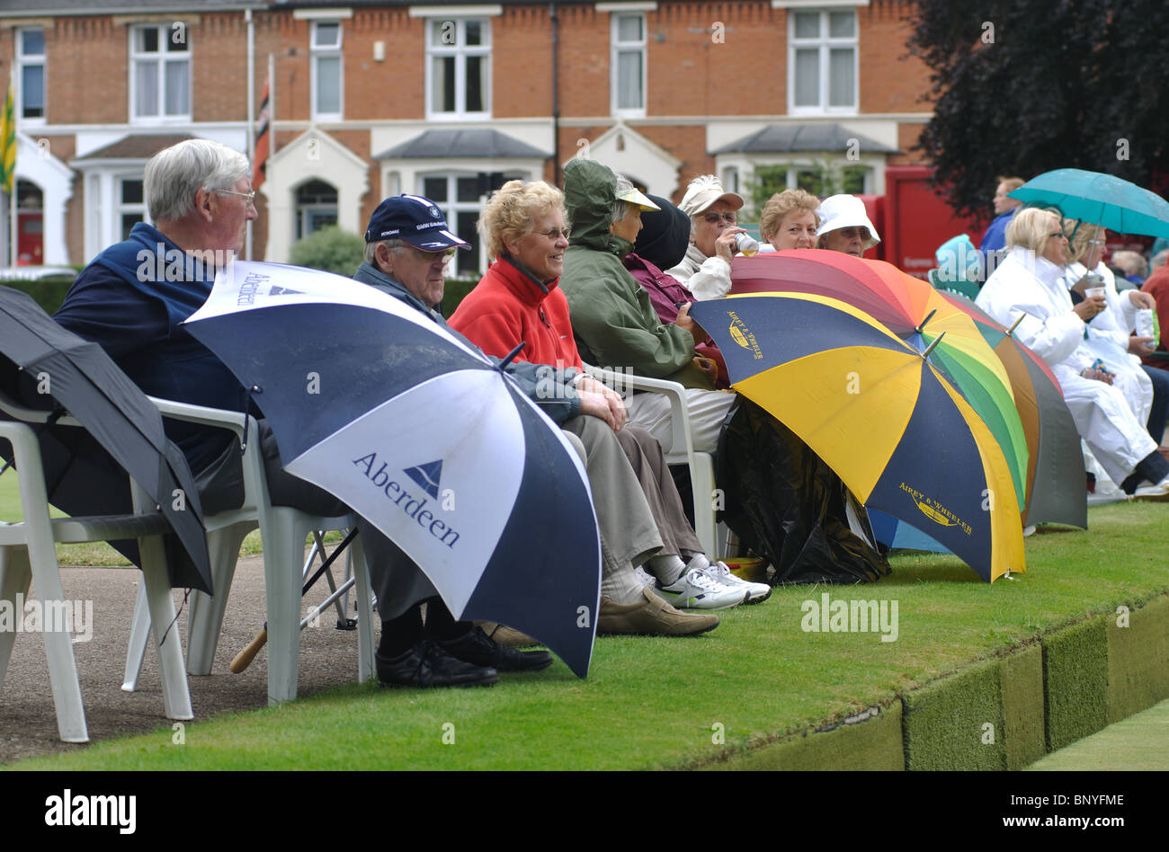 People with umbrellas watching ladies bowls matches Stock Photo