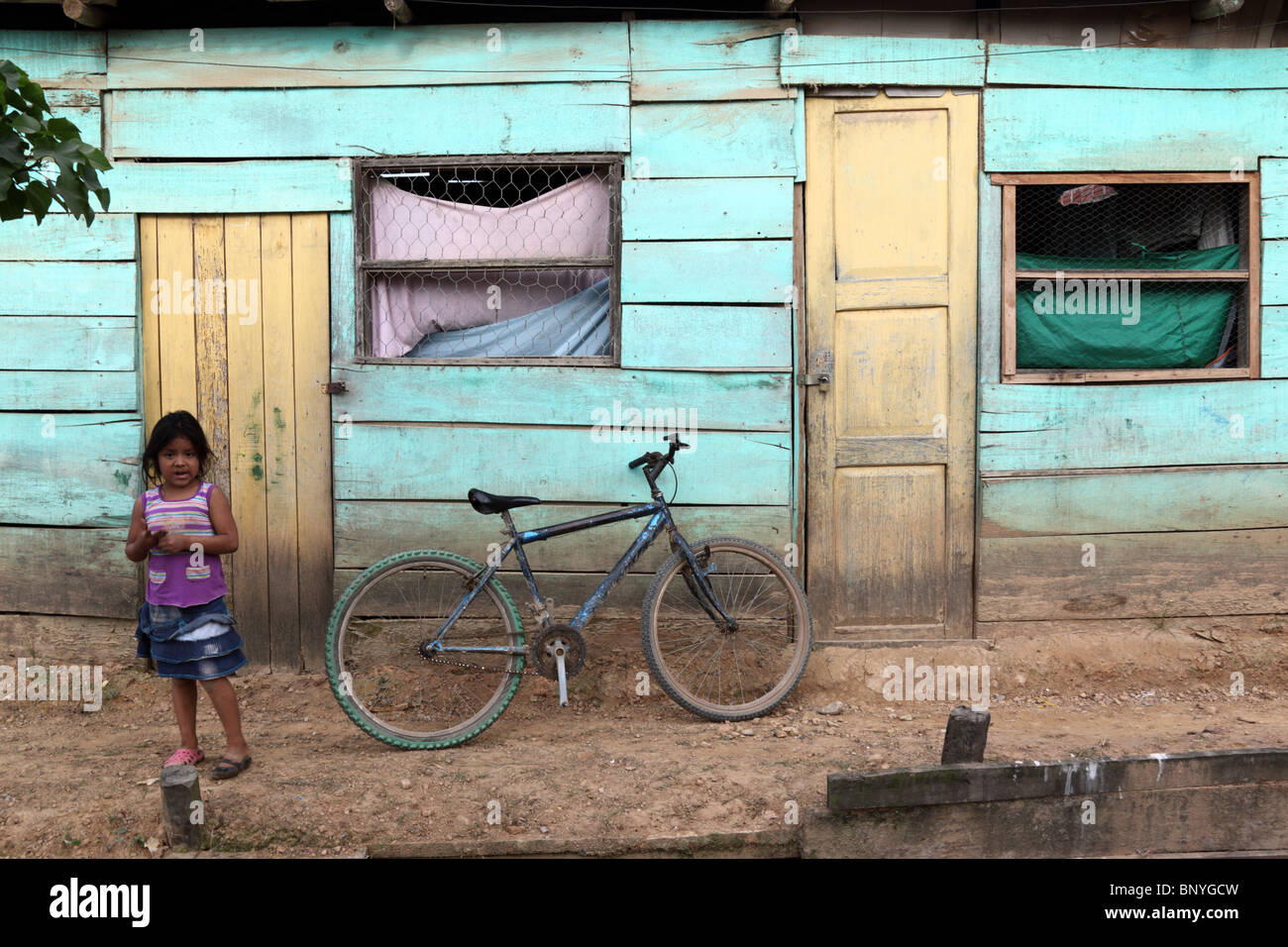 Girl and bicycle propped against wall of typical wooden house , Rurrenabaque , Bolivia Stock Photo