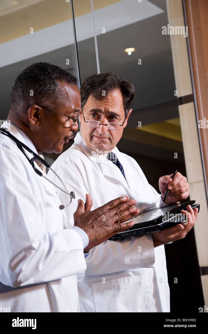 Two multiracial middle-aged doctors conversing Stock Photo