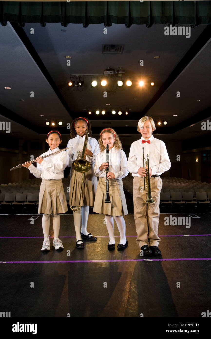 Young students playing musical instruments in school auditorium Stock Photo