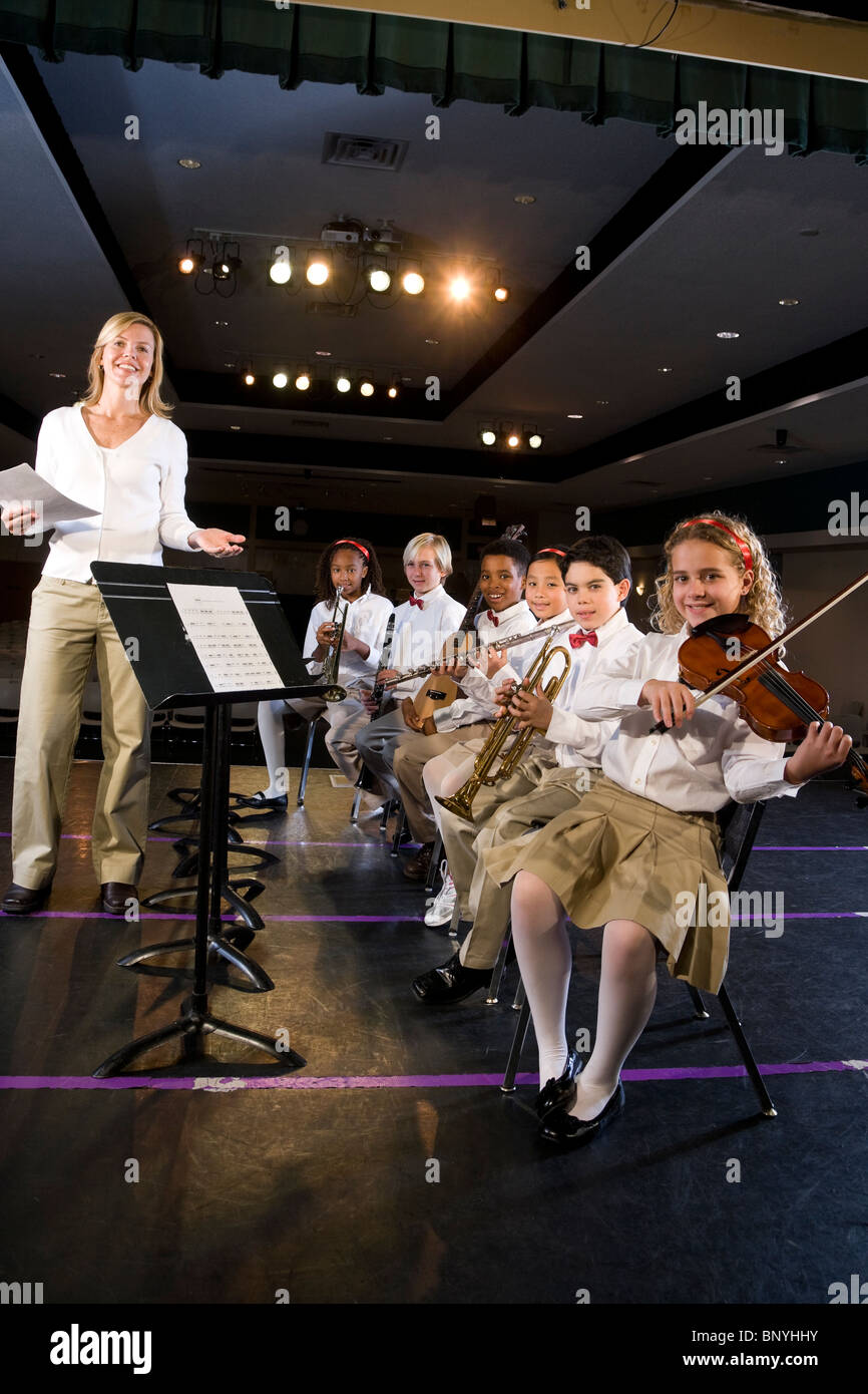 Young students playing musical instruments in school auditorium Stock