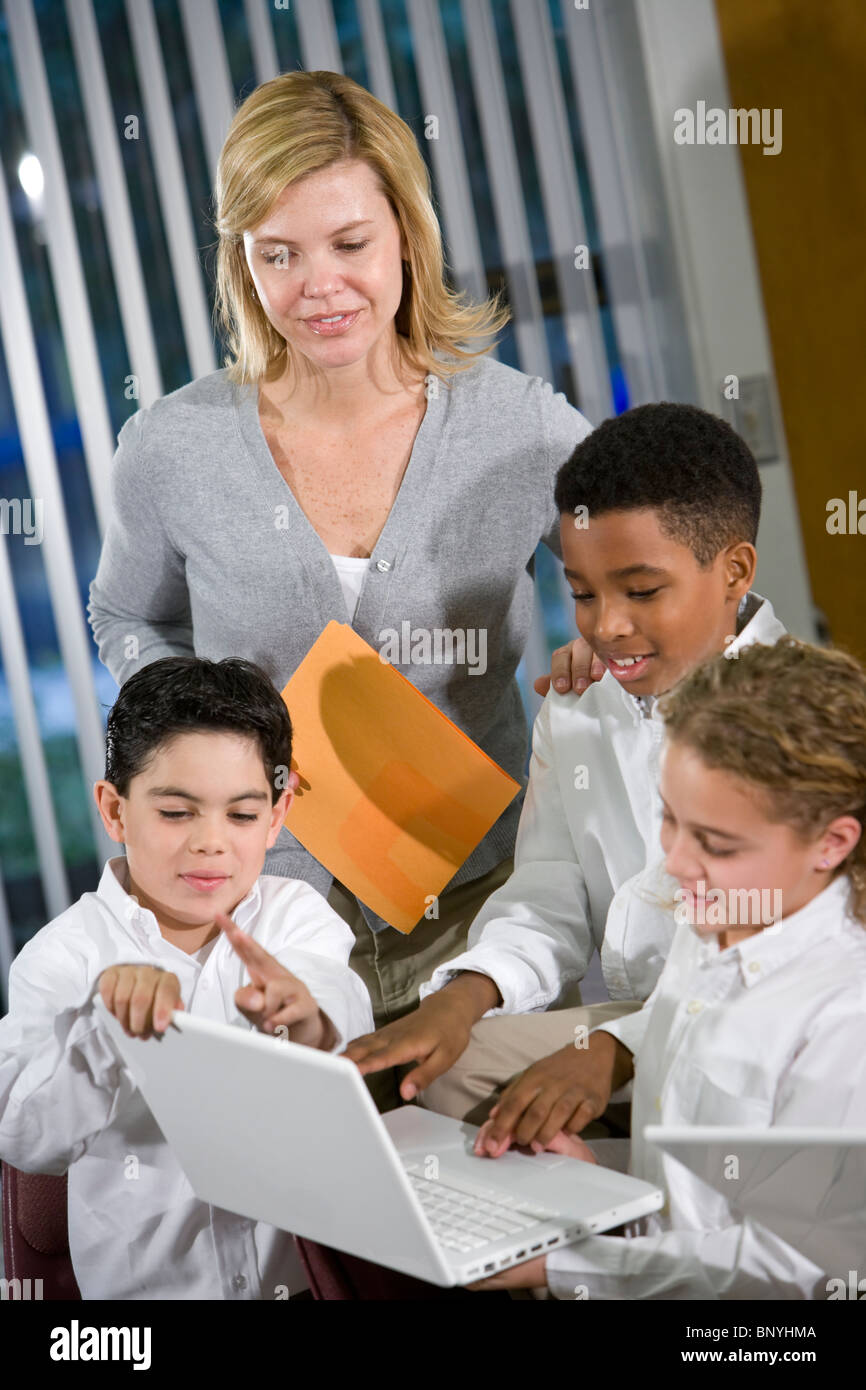 Teacher in class, elementary school children using laptops Stock Photo ...